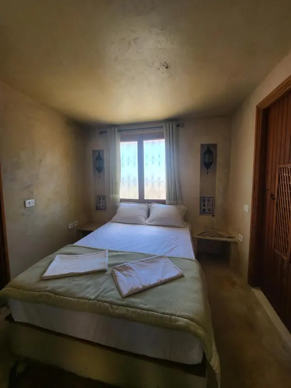 Une chambre lumineuse avec un lit recouvert d'un couvre-lit vert.