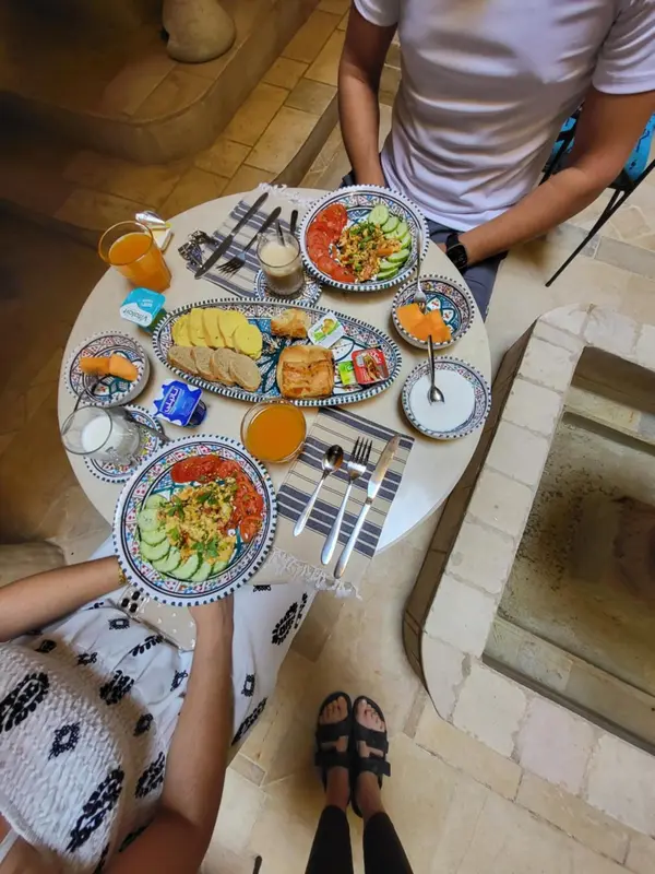 Une table ronde est dressée avec un assortiment de plats et de boissons.