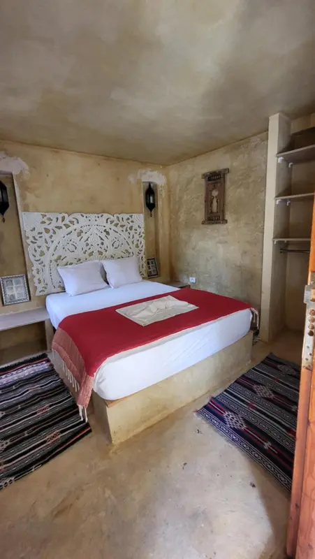 Une chambre à coucher avec un lit recouvert d'une courtepointe rouge et d'oreillers blancs.