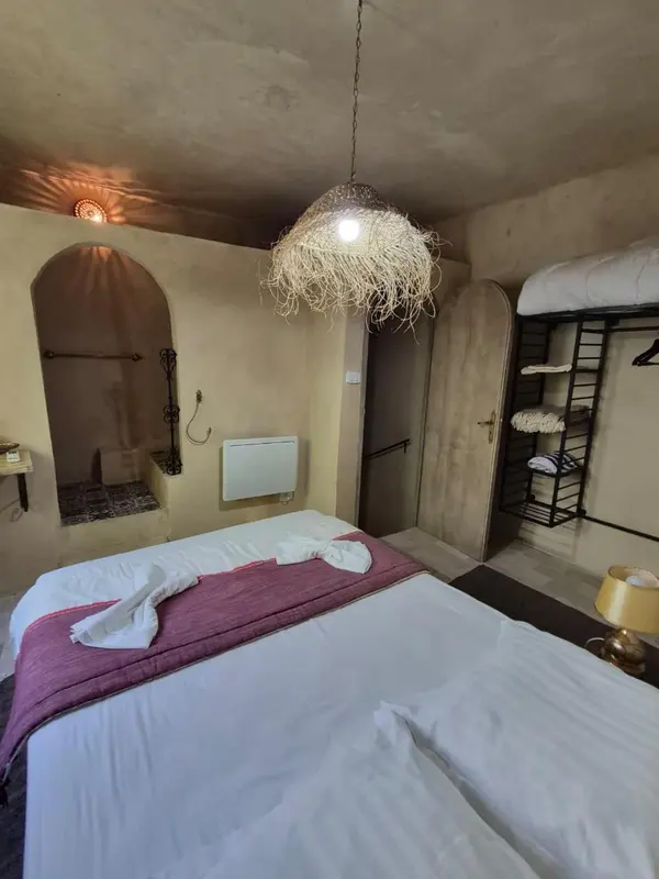 Une chambre à coucher avec un lit recouvert d'une courtepointe et un luminaire suspendu.