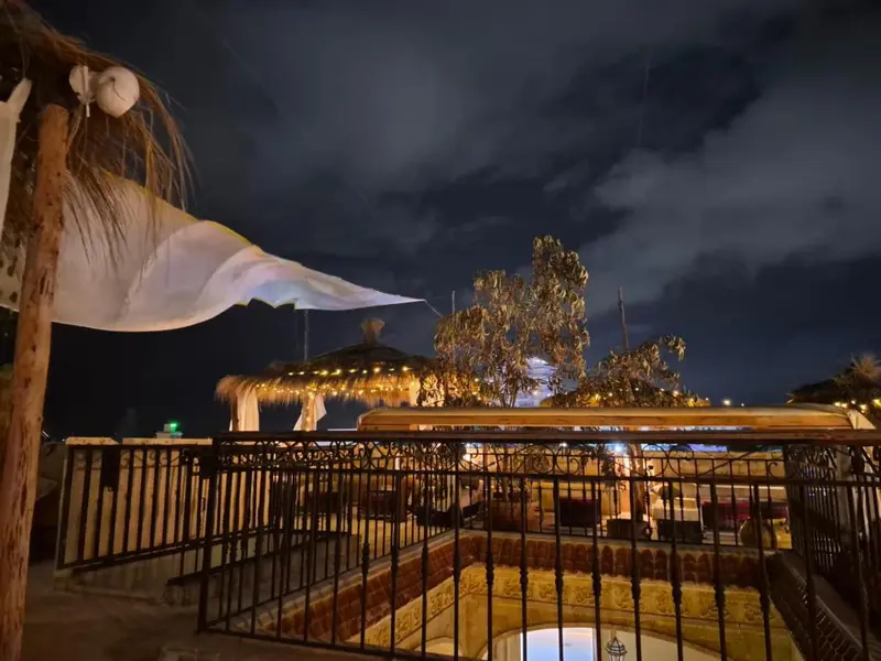 Terrasse ombragée avec mobilier de détente et éclairage nocturne.