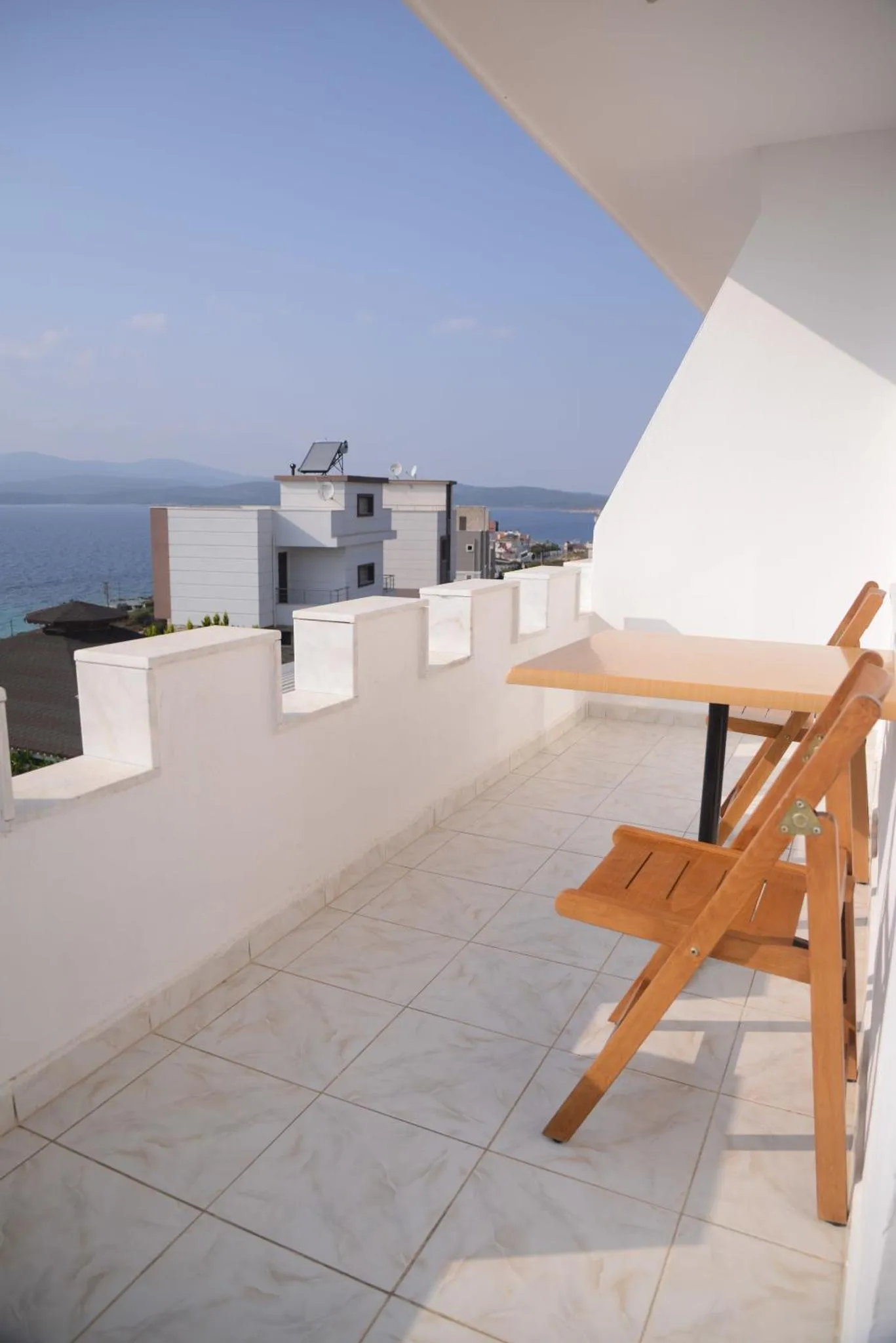 Terrasse avec table et chaises donnant sur une vue mer et des bâtiments.