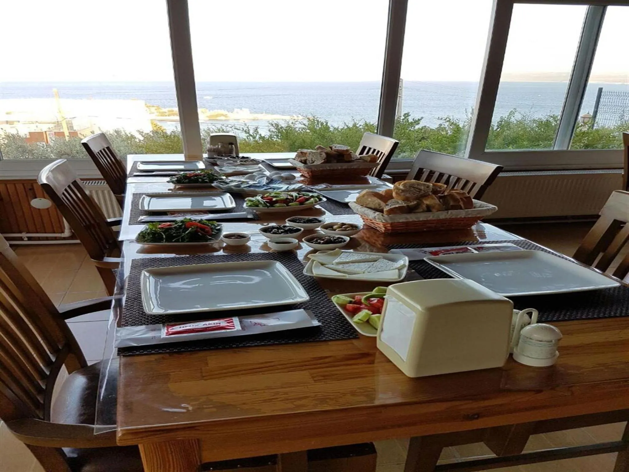 Une longue table est dressée pour un repas avec une vue sur la mer.