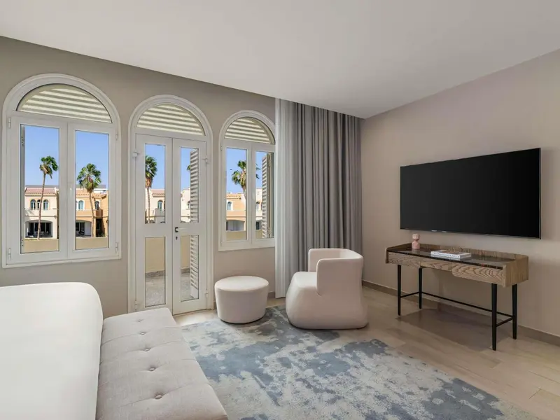 Une chambre lumineuse avec un coin salon et vue sur la végétation.