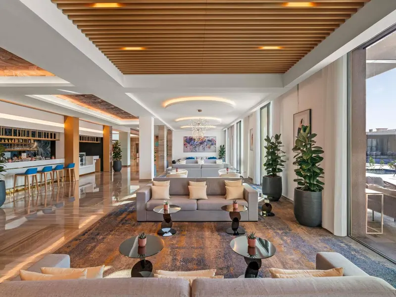 Un espace de détente intérieur avec canapés et tables basses sous un plafond en bois lambrissé.