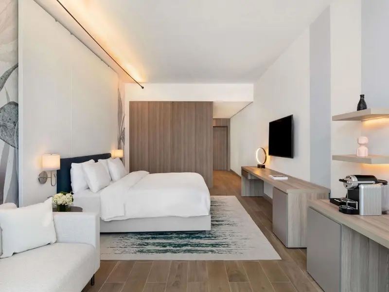 Chambre lumineuse avec un grand lit et un espace détente.