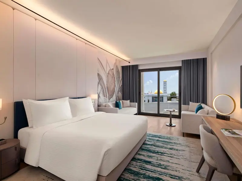 Une chambre lumineuse avec un grand lit et un coin salon.