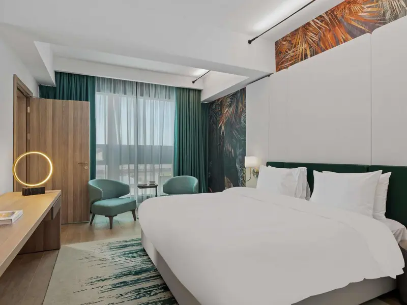 Une chambre lumineuse avec un grand lit et un coin salon.