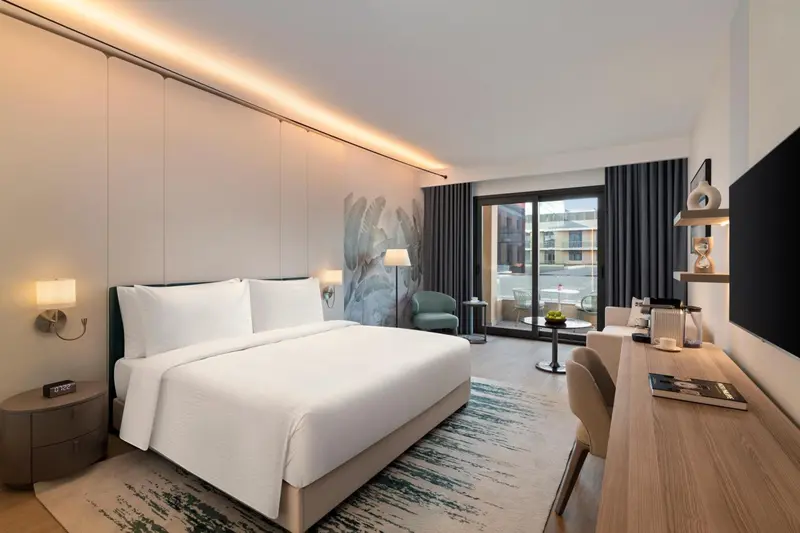 Chambre lumineuse avec un grand lit et un accès à une terrasse.