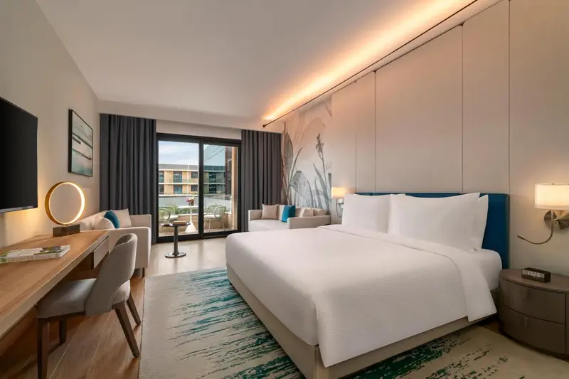 Chambre lumineuse avec un grand lit et un accès à une terrasse.
