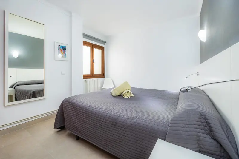 Une chambre lumineuse avec un grand lit et un miroir.