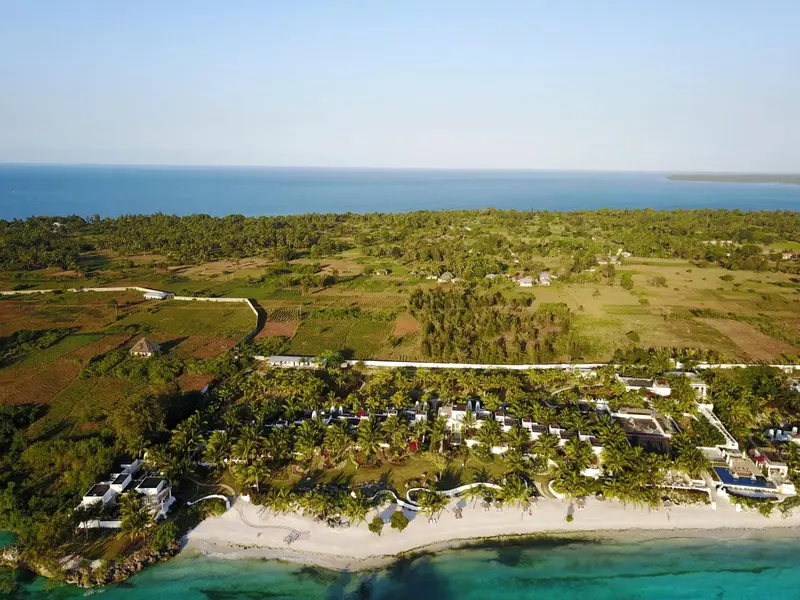 Vue aérienne d'un complexe hôtelier bordant une plage de sable blanc et une mer turquoise.
