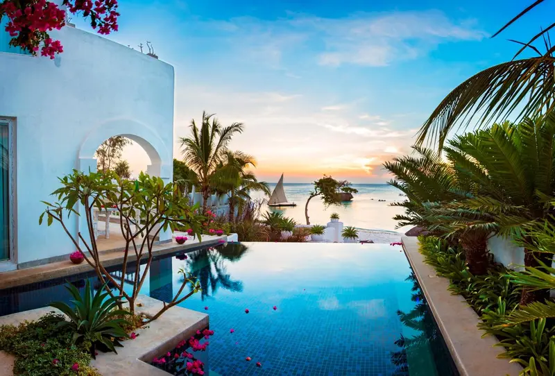 Une piscine à débordement surplombe la mer au coucher du soleil.