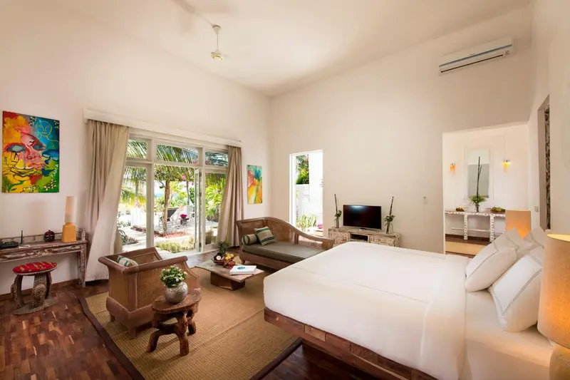 Une chambre lumineuse avec un lit king-size et un coin salon.