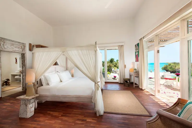 Une chambre lumineuse avec un lit à baldaquin donnant sur une vue sur la mer.