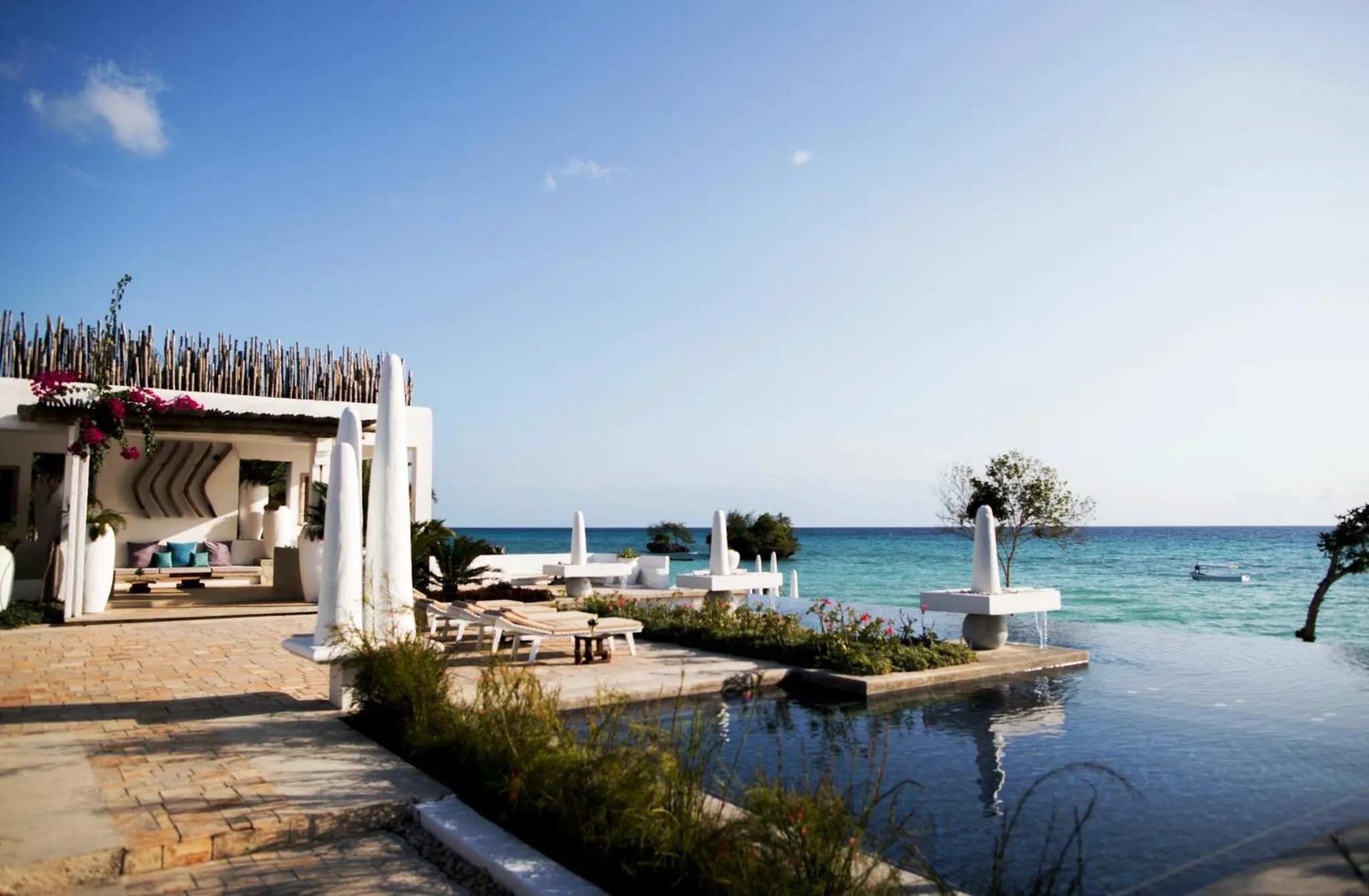 Terrasse avec transats et piscine à débordement face à la mer.