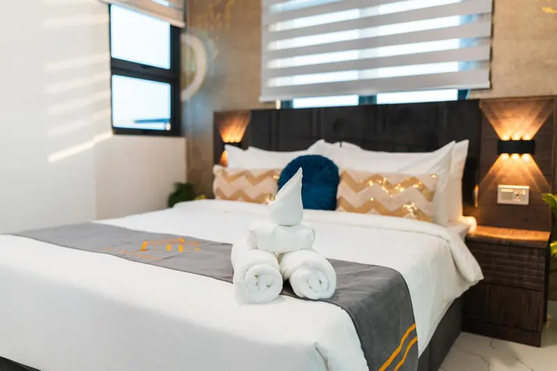 Lit préparé avec des serviettes en forme de cygne dans une chambre d'hôtel.