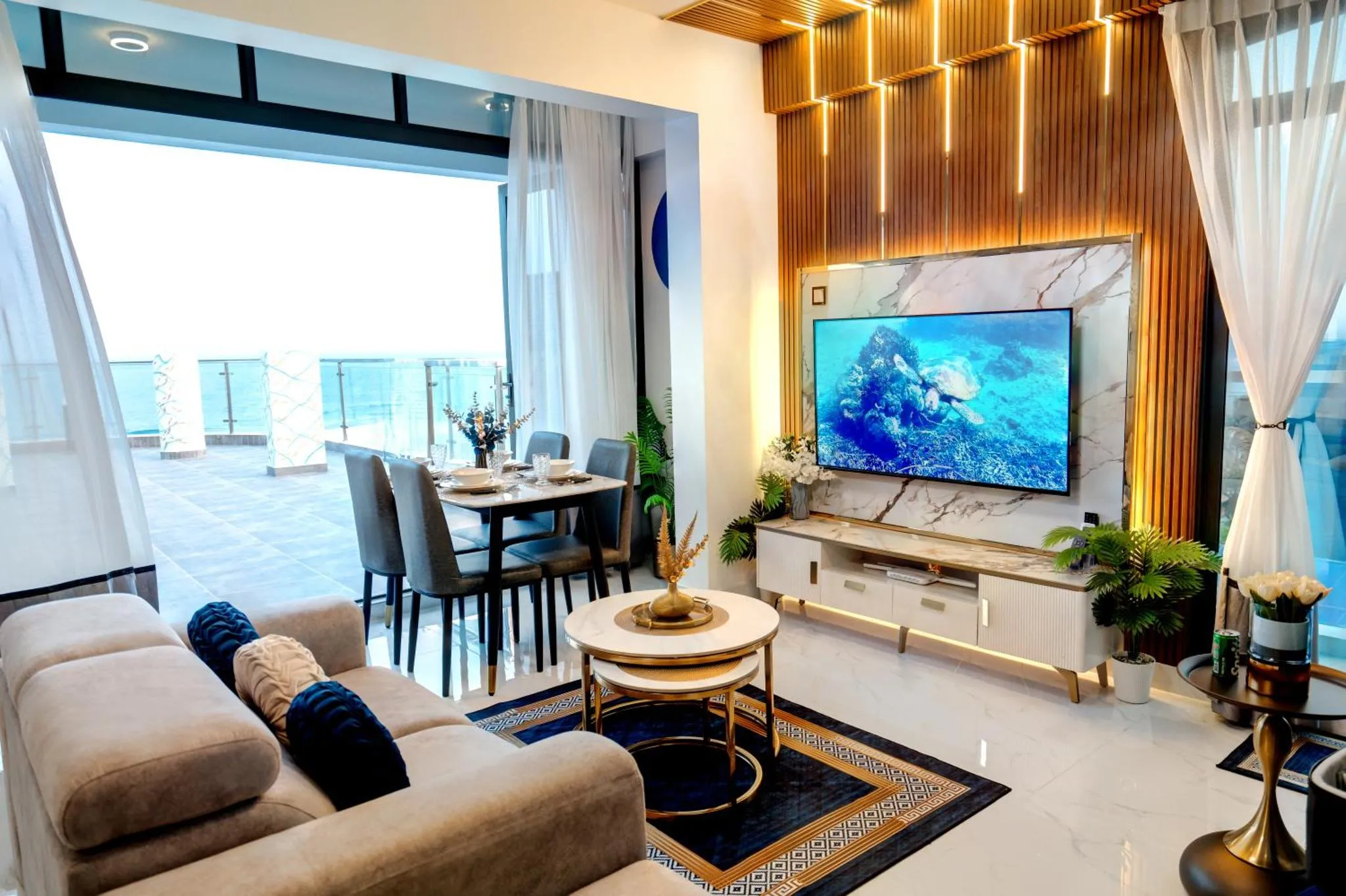 Un salon moderne s'ouvre sur une terrasse avec vue sur la mer.