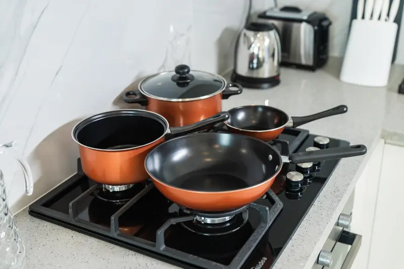 Des casseroles et poêles sont posées sur une plaque de cuisson.
