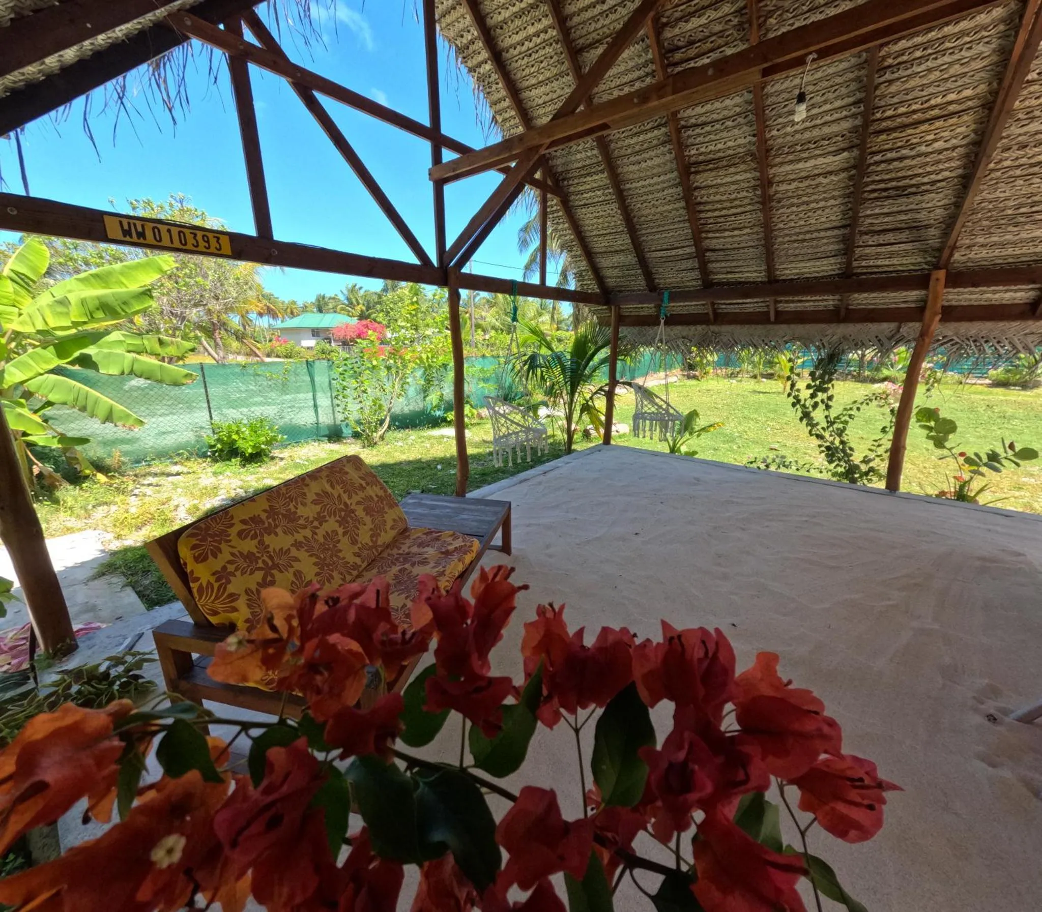 Espace de détente ombragé avec mobilier de jardin et végétation tropicale.