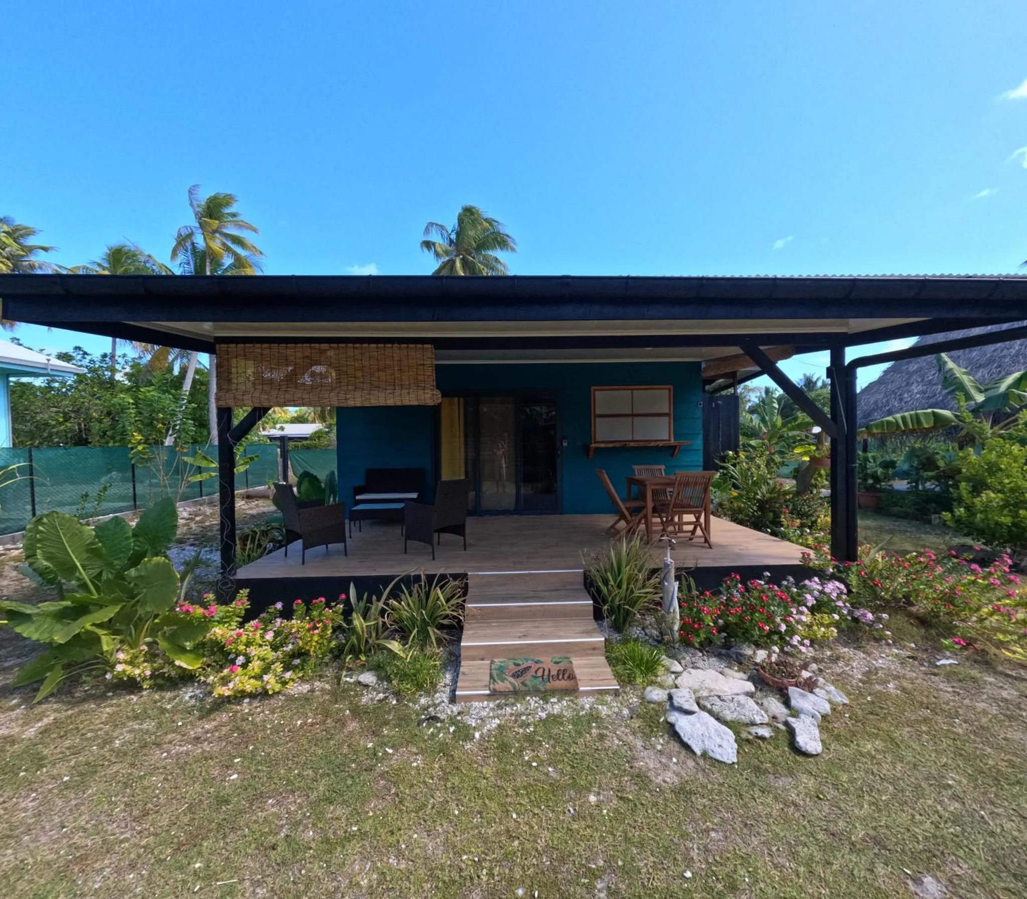 Une terrasse ombragée donne sur un bungalow coloré entouré de végétation tropicale.