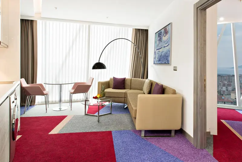 Un salon moderne avec canapé d'angle, table basse et tapis coloré.
