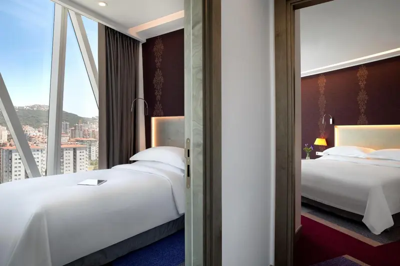 Chambre d'hôtel moderne avec un grand lit et une vue sur la ville.
