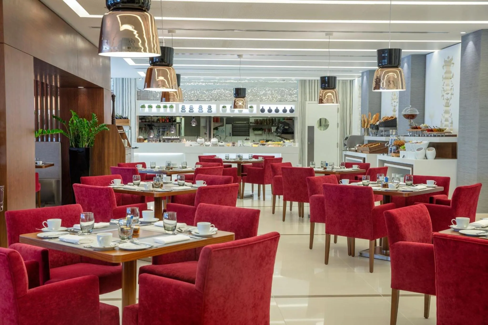 Une salle lumineuse avec des tables dressées pour le petit-déjeuner.