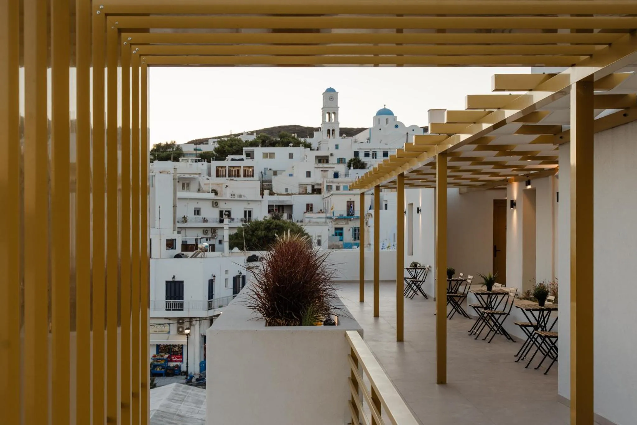 Terrasse ombragée donnant sur un village blanc et bleu.