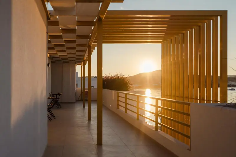 Terrasse ombragée avec vue sur la mer au coucher du soleil.