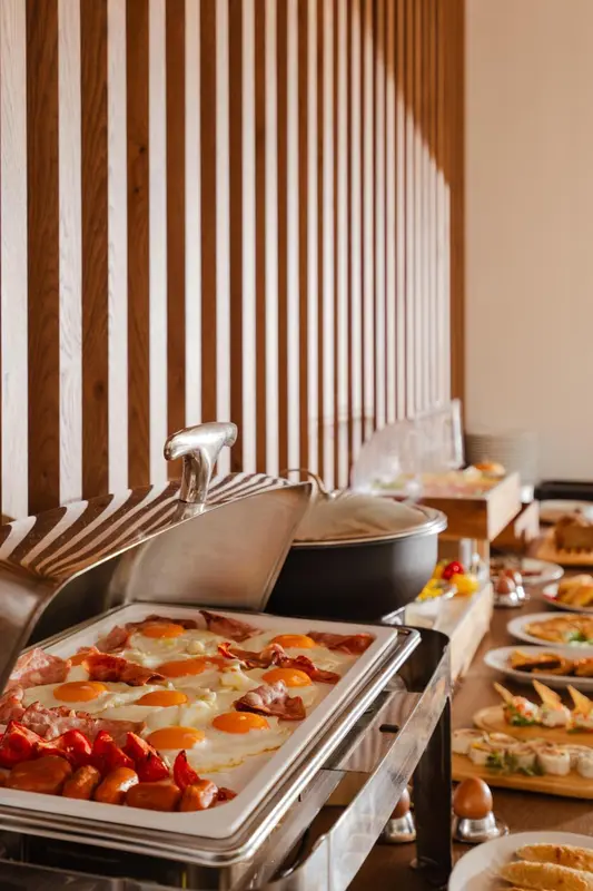 Un buffet propose des œufs, du bacon et des saucisses.