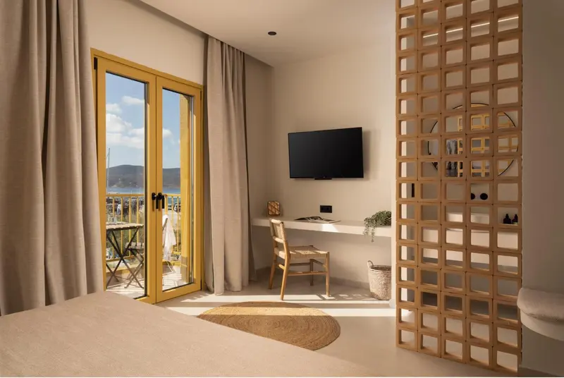 Une chambre lumineuse avec un bureau et un accès à un balcon.