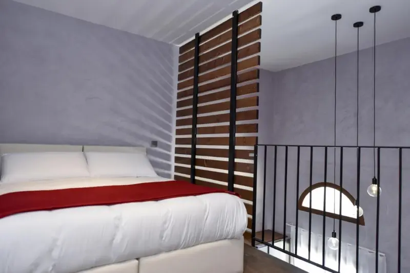 Une chambre avec un lit recouvert d'une courtepointe rouge et un décor mural en bois.