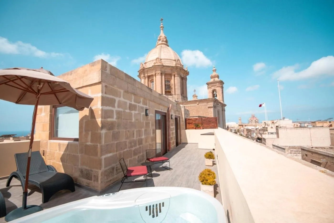 Terrasse avec jacuzzi et vue sur un édifice religieux et la mer.