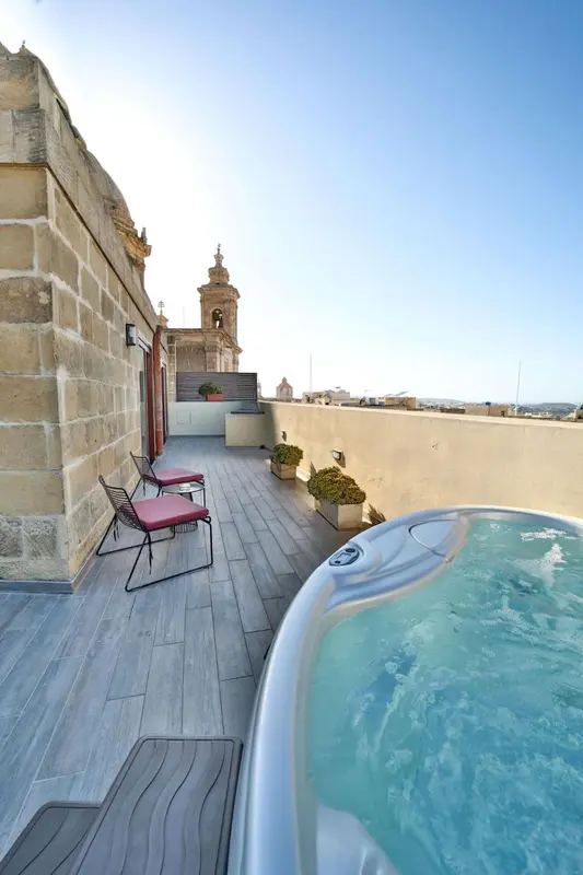 Terrasse avec jacuzzi et mobilier de jardin offrant une vue sur un paysage urbain.