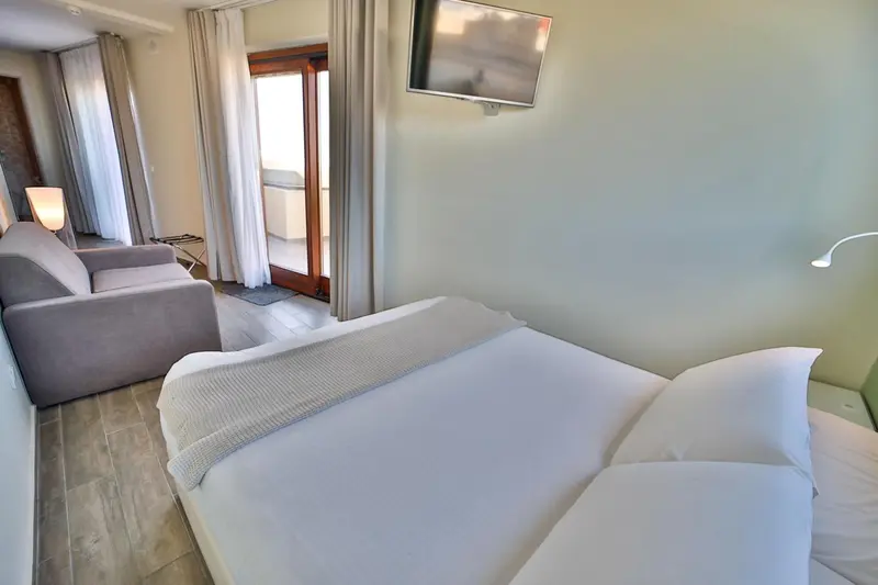 Une chambre lumineuse avec un lit fait et un coin salon.