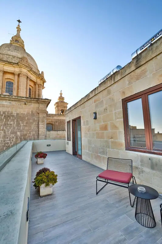 Terrasse aménagée avec mobilier de jardin et vue sur un édifice religieux.