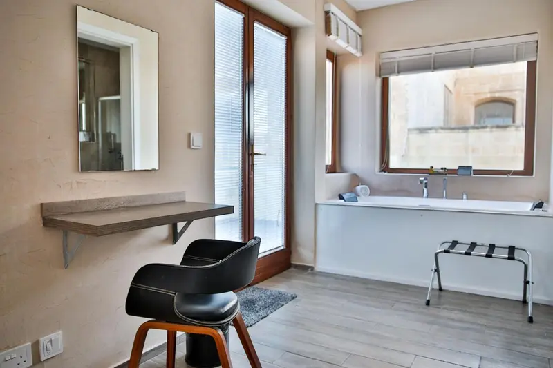 Une salle de bain lumineuse avec baignoire et coiffeuse.