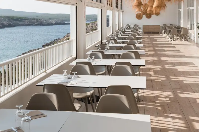 Une terrasse spacieuse avec des tables et des chaises face à la mer.