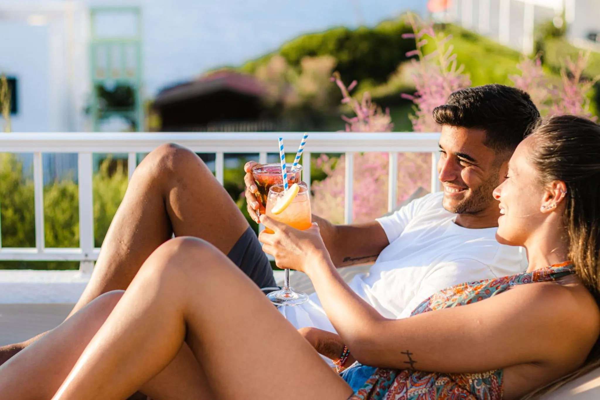 Un couple se détend avec des boissons sur une terrasse ensoleillée.