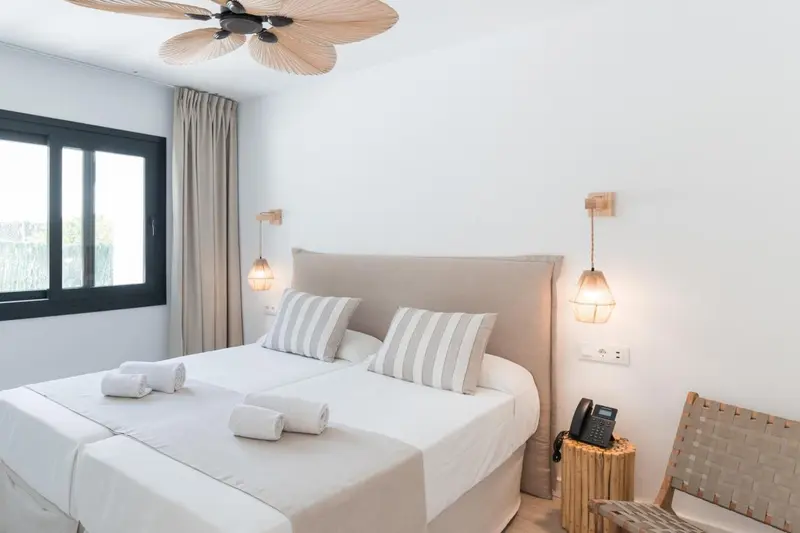 Une chambre lumineuse avec un grand lit et des luminaires suspendus.