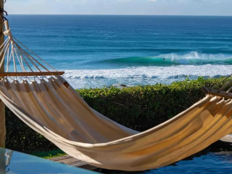 Un hamac blanc est suspendu au-dessus d'une piscine avec vue sur l'océan.