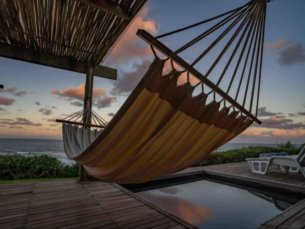 Un hamac est suspendu sur une terrasse en bois avec vue sur la mer.