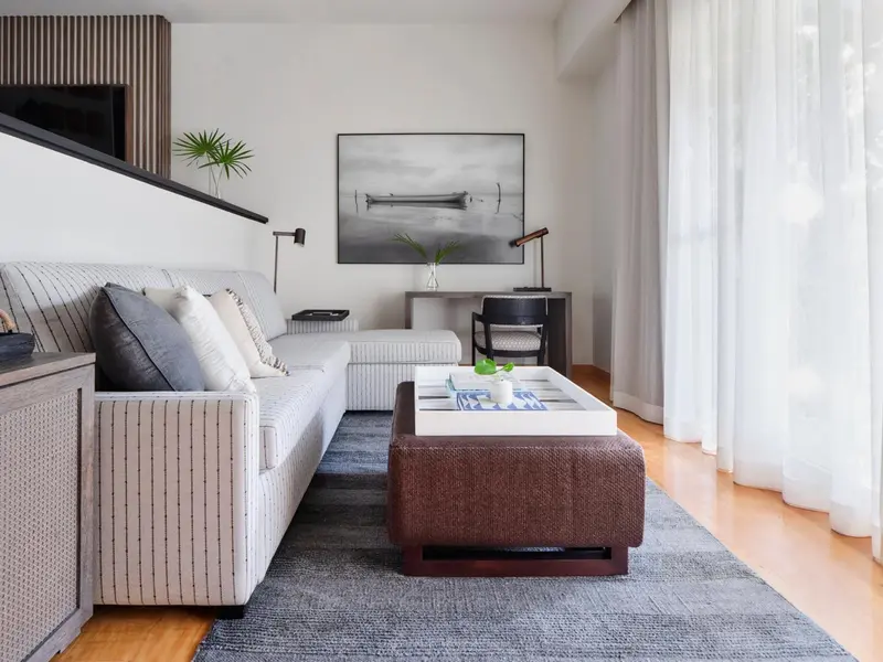 Un salon moderne avec un canapé d'angle, une table basse et une grande fenêtre.