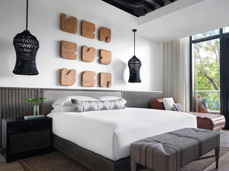 Une chambre lumineuse avec un grand lit et des suspensions décoratives.