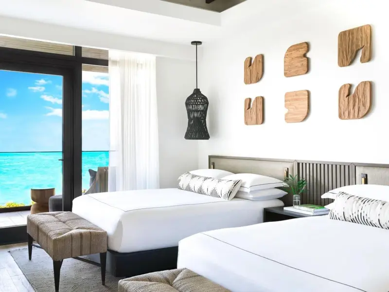 Une chambre lumineuse avec deux lits et vue sur la mer.