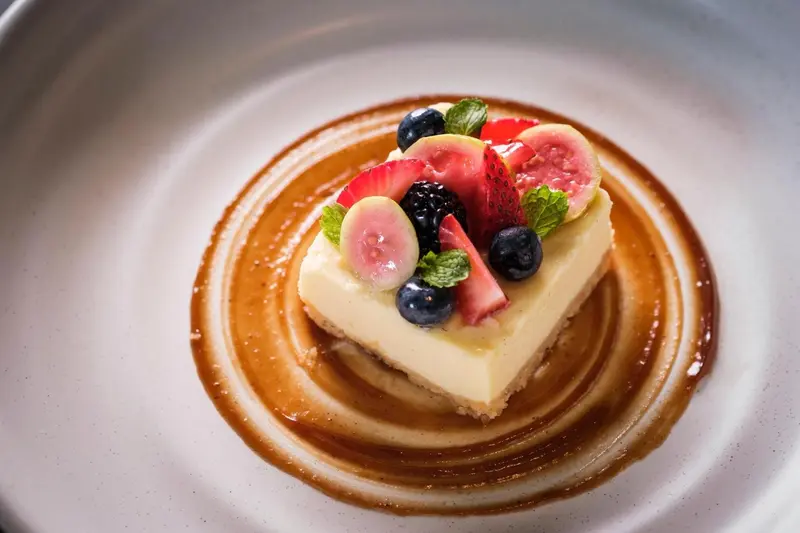 Un dessert crémeux aux fruits frais est présenté sur une assiette blanche.