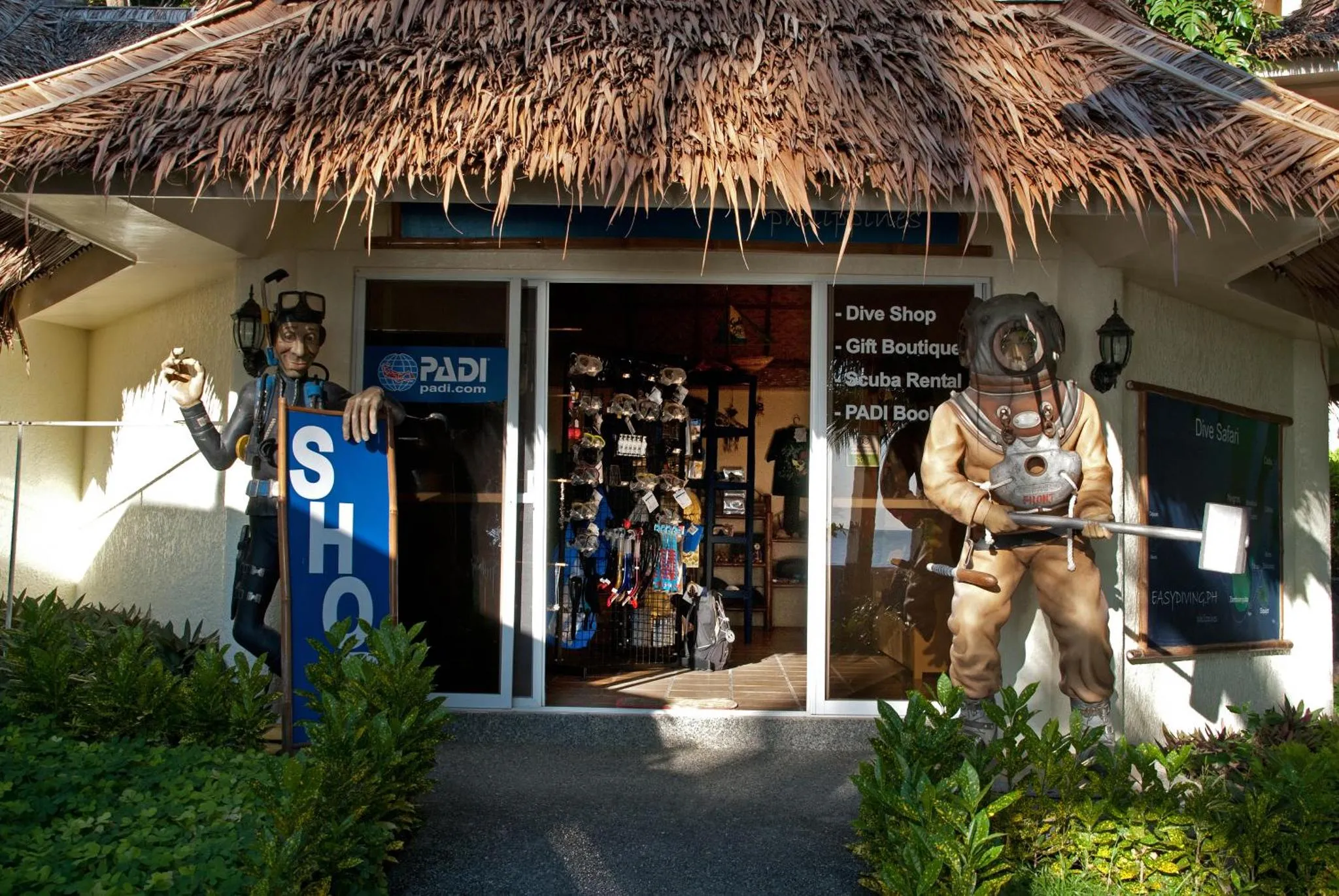 Entree d'un commerce avec des mannequins de plongeurs et des articles de sport nautique.