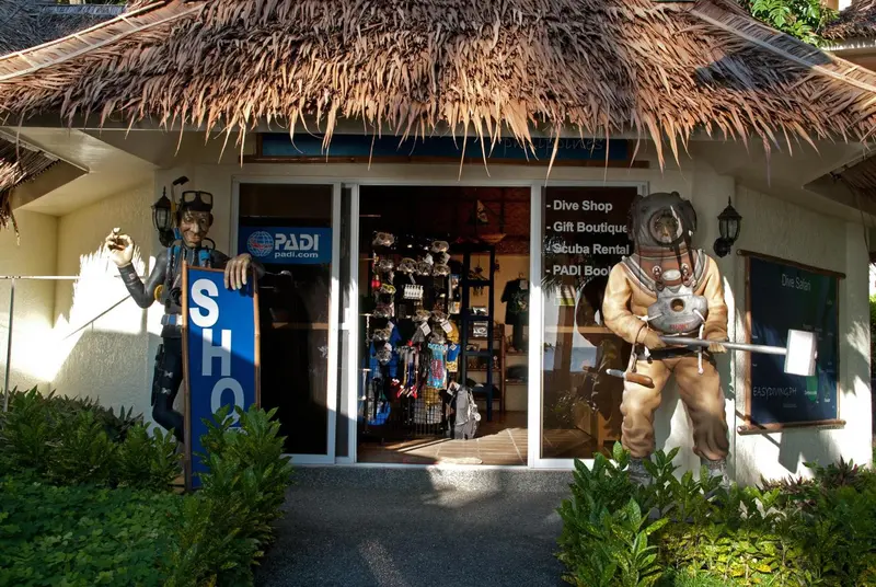 Entree d'un commerce avec des mannequins de plongeurs et des articles de sport nautique.