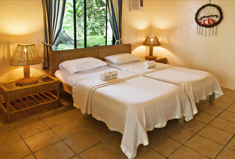 Une chambre lumineuse avec deux lits simples et une décoration tropicale.